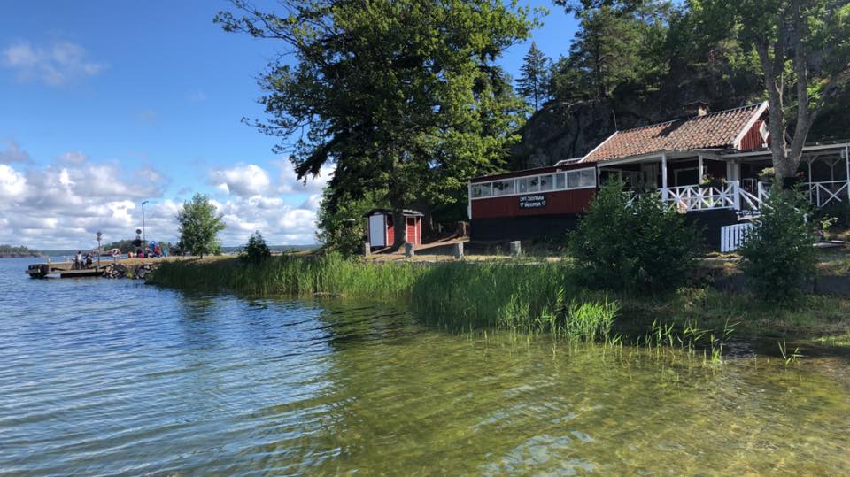 rött hus med vita knutar nära vattnet och grönska