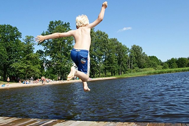 Barn som hoppar i vattnet från brygga i Värmdö